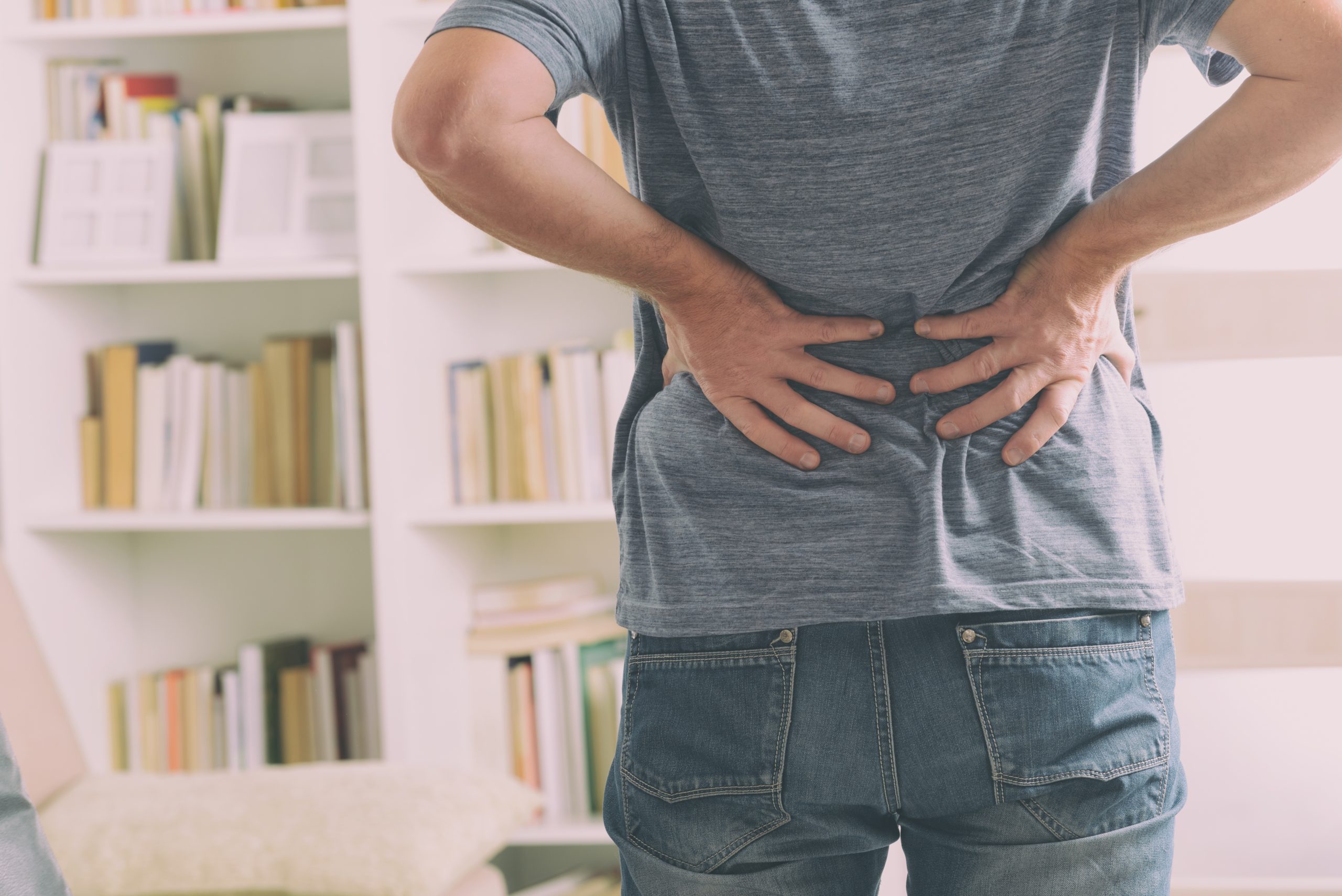 Man in home office suffering from low back pain standing.
